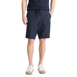 Someone stands against a plain background wearing a navy t-shirt, Vince Hemp Drawstring Short in navy, and white sneakers with gum soles.