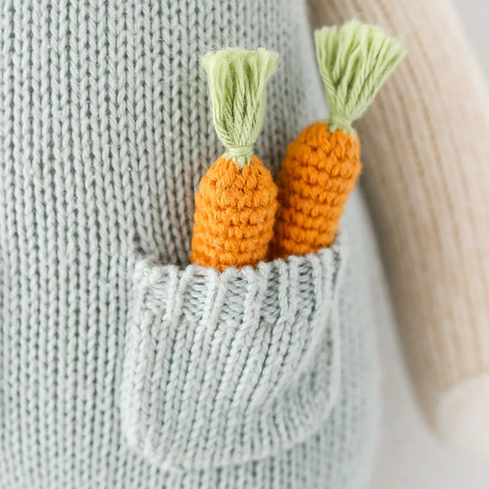 Two knitted orange carrots with green tops add a playful touch to the pocket of the light gray Henry the Bunny - Regular 20" doll by Cuddle + Kind. Perfect for any carrot connoisseur!.