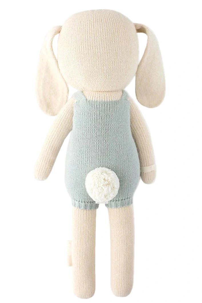 Henry the Bunny - Little 13" by Cuddle + Kind is a knitted stuffed bunny, shown from the back in a light blue outfit with a white pom-pom tail—an adorable gift for bunny lovers and friends who enjoy growing things together.