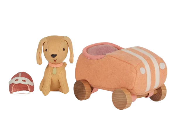 The Olli Ella Holdie Dog Go set features a stuffed toy dog, a matching car with wooden wheels, and a tiny fabric helmet, all arranged on a white background.