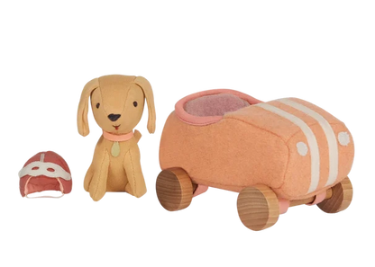 The Olli Ella Holdie Dog Go set features a stuffed toy dog, a matching car with wooden wheels, and a tiny fabric helmet, all arranged on a white background.