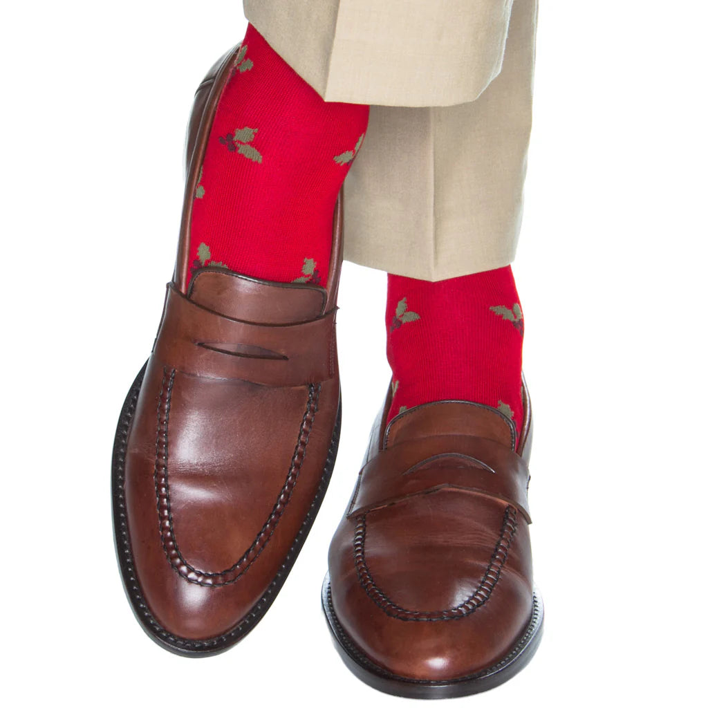 A person wearing beige pants, brown leather loafers, and Dapper Classics Red with Burgundy Berry and Pine Green Holly Wool Sock Linked-Toe Mid-Calf.