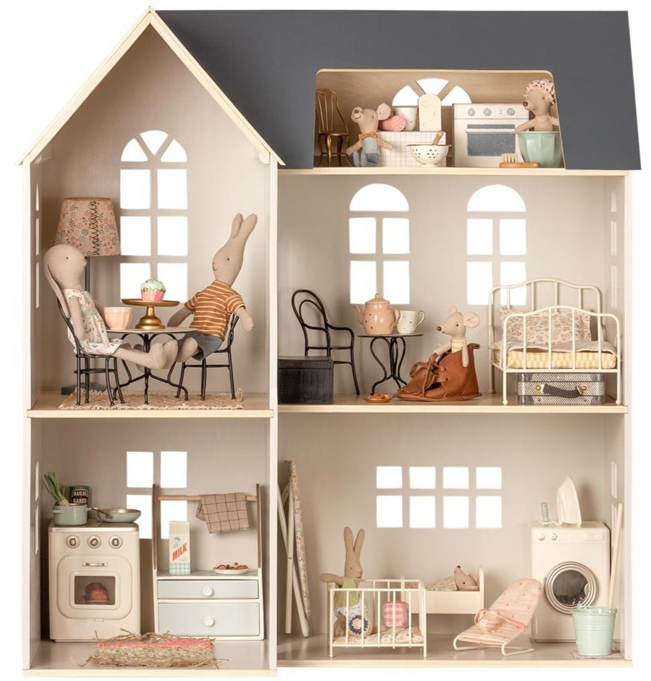 Introducing the Maileg Dollhouse, House of Miniature: a beautifully crafted wooden dollhouse with six rooms, each thoughtfully furnished with intricate Maileg miniature furniture. Adorable rabbit characters inhabit this home, bringing life to spaces such as the kitchen, bedroom, living area, and laundry space. This easy-to-assemble dollhouse is perfect for endless hours of imaginative play.