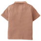 The Baby Boys' Timmy Waffle Knit Polo Shirt by Gingersnaps is a light brown, short-sleeve top with a collar and a small square patch at the upper back.