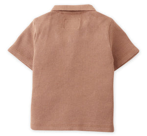 The Baby Boys' Timmy Waffle Knit Polo Shirt by Gingersnaps is a light brown, short-sleeve top with a collar and a small square patch at the upper back.