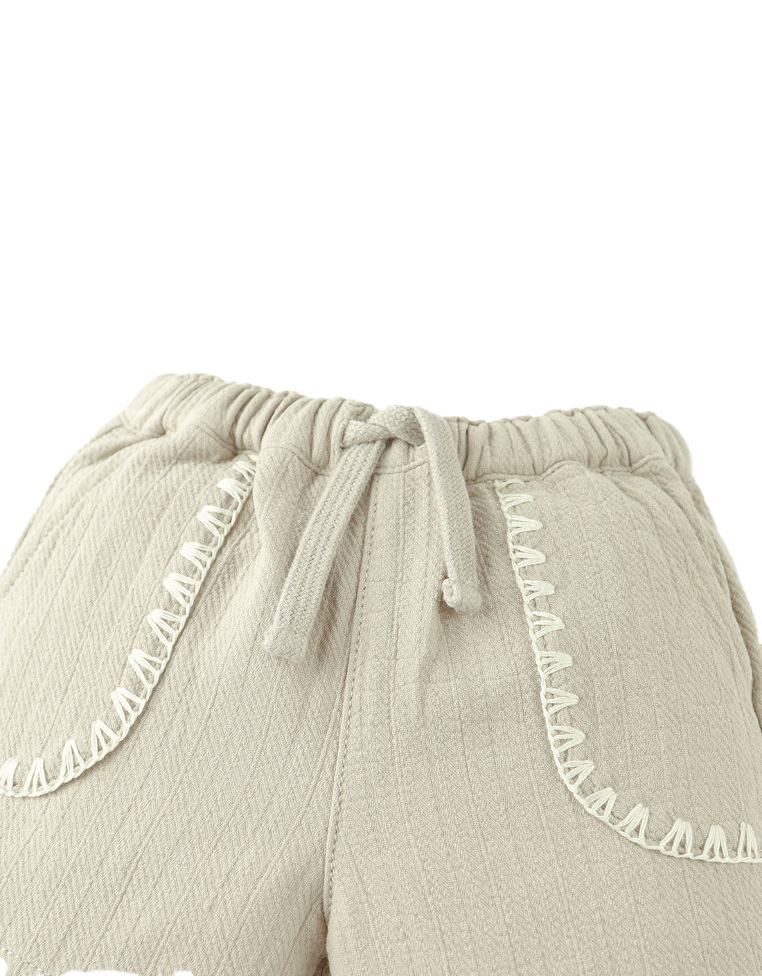 Close-up of Gingersnaps Baby Boys’ Marlow Drawstring Shorts featuring beige textured cotton, an elastic waistband, drawstring tie, and contrast stitching—a comfy pick for casual kids' style.