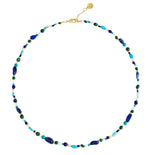The Milos Beaded Necklace by Anabel Aram features small blue, turquoise, green, and gold beads with a gold clasp and adjustable chain.