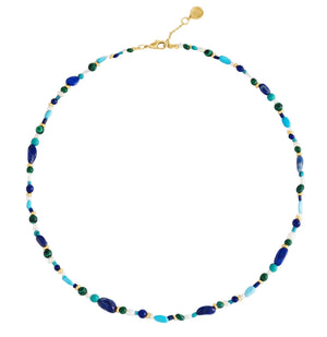 The Milos Beaded Necklace by Anabel Aram features small blue, turquoise, green, and gold beads with a gold clasp and adjustable chain.