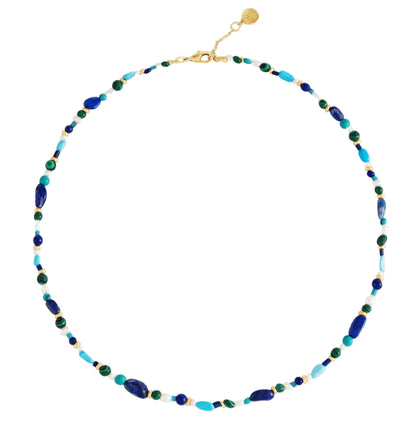 The Milos Beaded Necklace by Anabel Aram features small blue, turquoise, green, and gold beads with a gold clasp and adjustable chain.