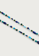 The Milos Beaded Necklace by Anabel Aram features lapis lazuli, turquoise, green, and gold beads arranged on a white background.