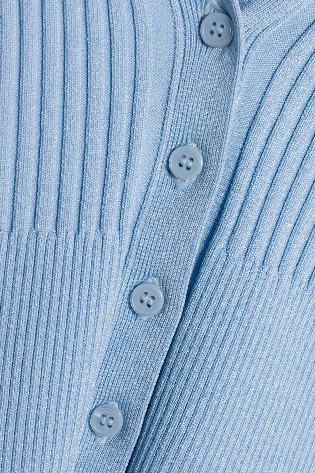 Close-up of the Simkhai Ailany Cardigan, a light blue ribbed knit cropped style featuring matching blue buttons in a vertical row down the front.