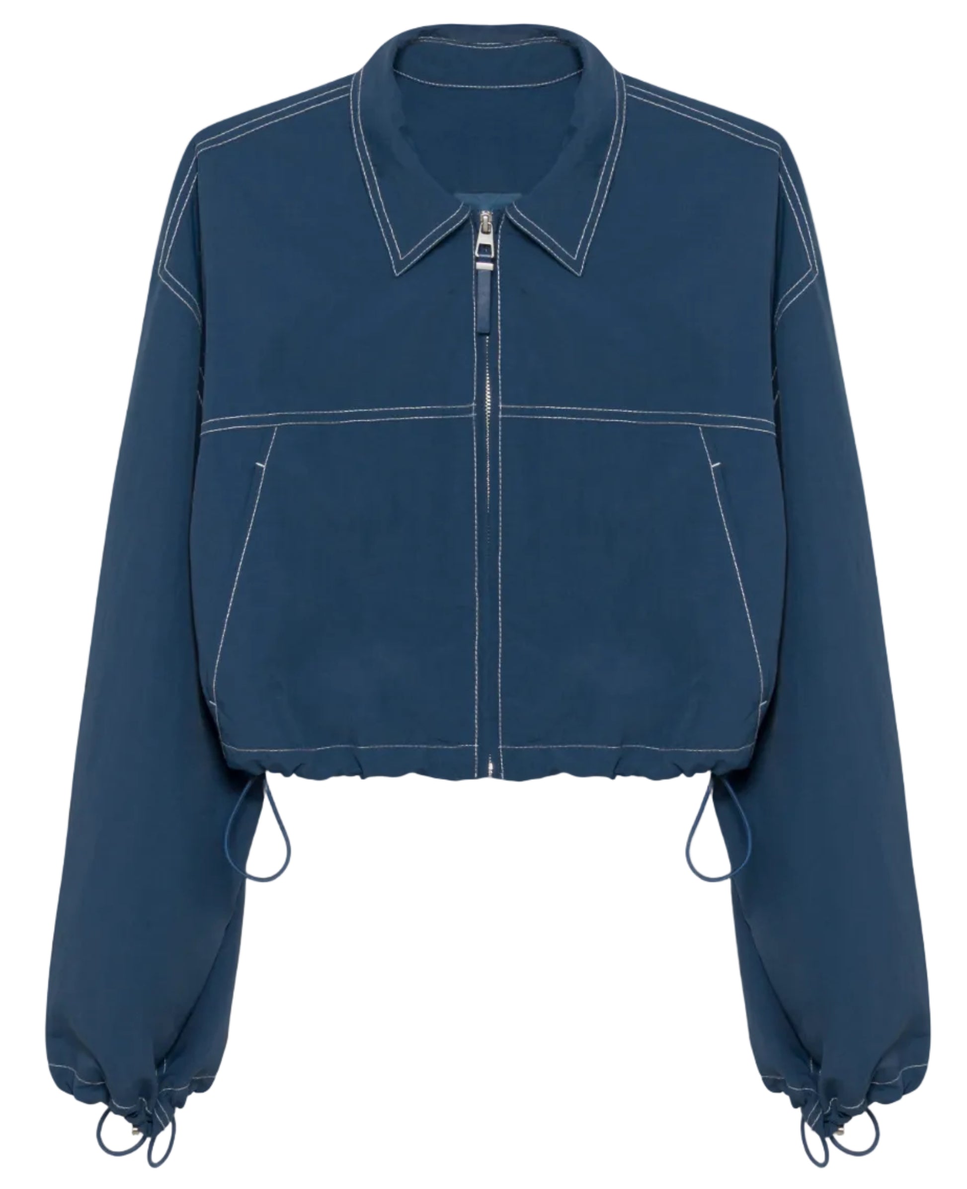 The Colsen Cotton Cropped Jacket by Simkhai features dark indigo cotton, white contrast stitching, long sleeves, a collar, and adjustable drawstrings at the hem and cuffs.