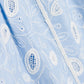 Close-up of delicate light blue fabric with white floral embroidery and lace-like details from the Simkhai Audria Belted Midi Dress, showcasing its intricate patterns and elegant texture.