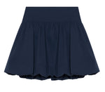 The Pippa Bubble Mini Skirt by Simkhai is a navy blue cotton poplin skirt with a gathered waist and subtle balloon hem for volume, shown against a white background.
