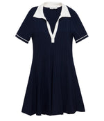 The Simkhai Page Knit Polo Mini Dress is a short-sleeved, navy blue mini dress with a pleated skirt, white collar, and white sleeve trim.