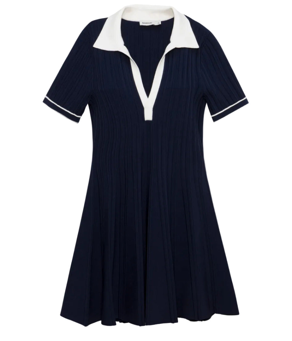 The Simkhai Page Knit Polo Mini Dress is a short-sleeved, navy blue mini dress with a pleated skirt, white collar, and white sleeve trim.