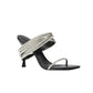 The Simkhai Infinity Crystal Strap Siren Sandal features a black pointed toe, slim sole, single front strap, and metallic silver straps wrapping the upper foot and ankle—ideal for elevating elegant evening looks.