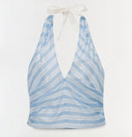 The Caprie Halter Top by Simkhai features light blue and white stripes in soft yarn-dyed satin, a deep V-neck, and a white ribbon neck tie, shown against a plain white background.