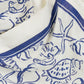 Close-up of cream-colored fabric with blue seashell, starfish, and marine motif line drawings, finished with a blue border—perfect for the Darbie Linen Mini Dress by Simkhai.