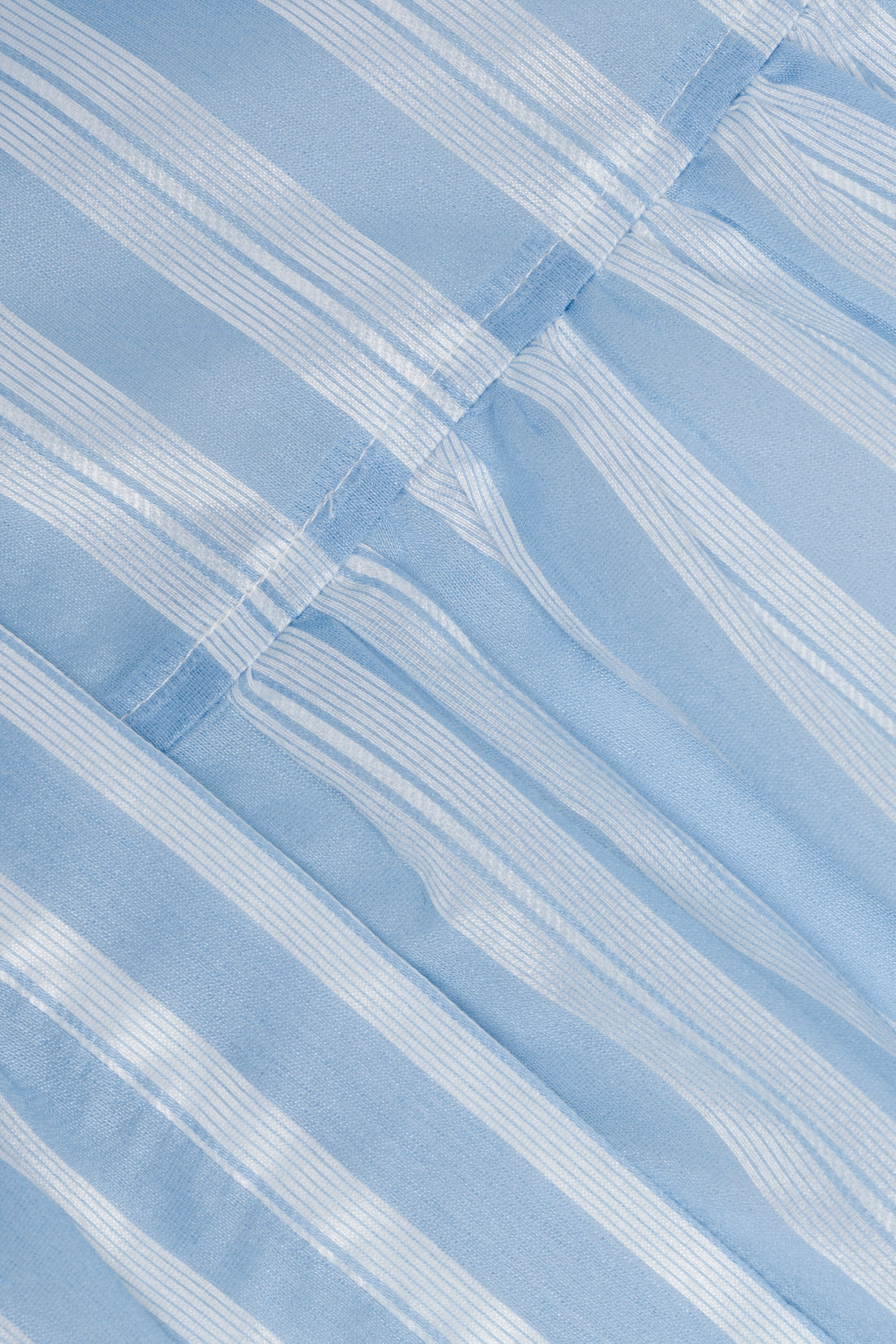 Close-up of light blue and white striped fabric with seam and gathered stitching from the Crissy Stripe Dress by Simkhai.