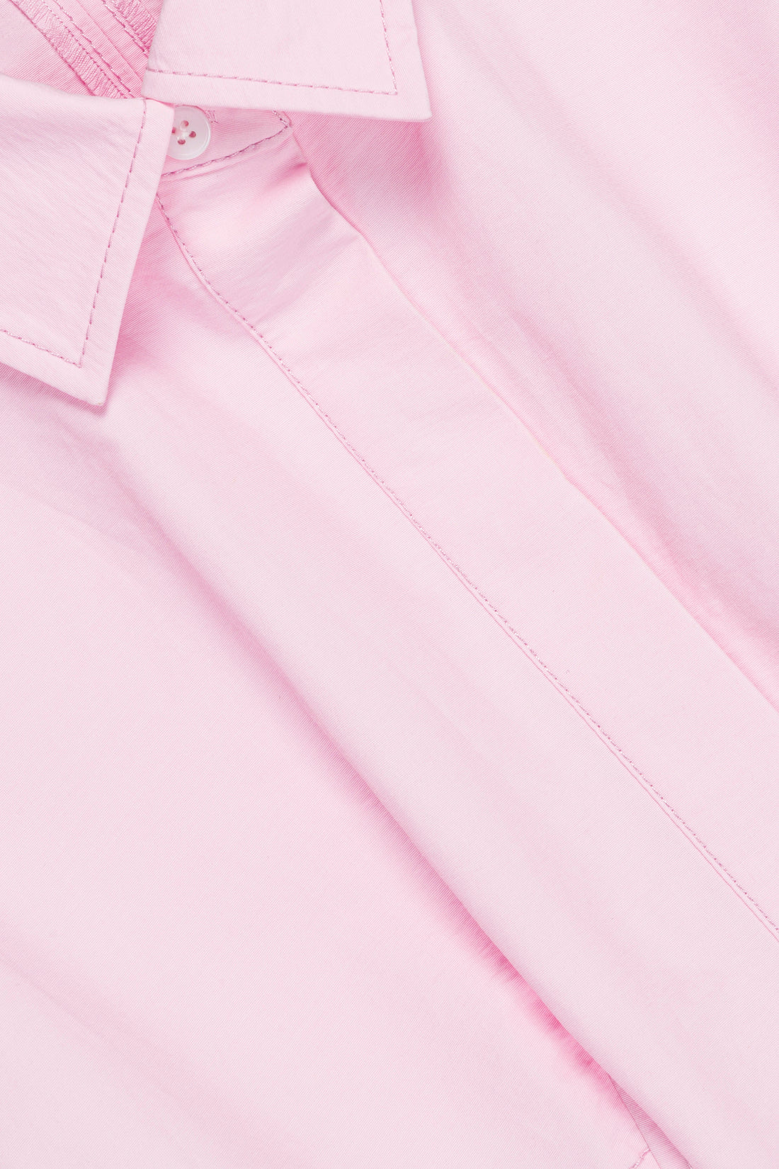 Close-up of the Clemmie Mini Dress by Simkhai in light pink, featuring a collared neckline, visible collar, button detail, and central seam with prominent stitching.