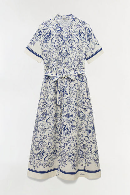 The Simkhai Audria Linen Midi Dress features a white short-sleeve design with a belted waist and blue marine-inspired seashell and starfish print, shown on a plain background.