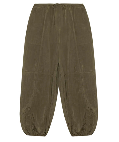 The Simkhai Freya Parachute Pant in olive green offers a loose fit with a drawstring waistband, visible seam details, and elasticated ankle cuffs.