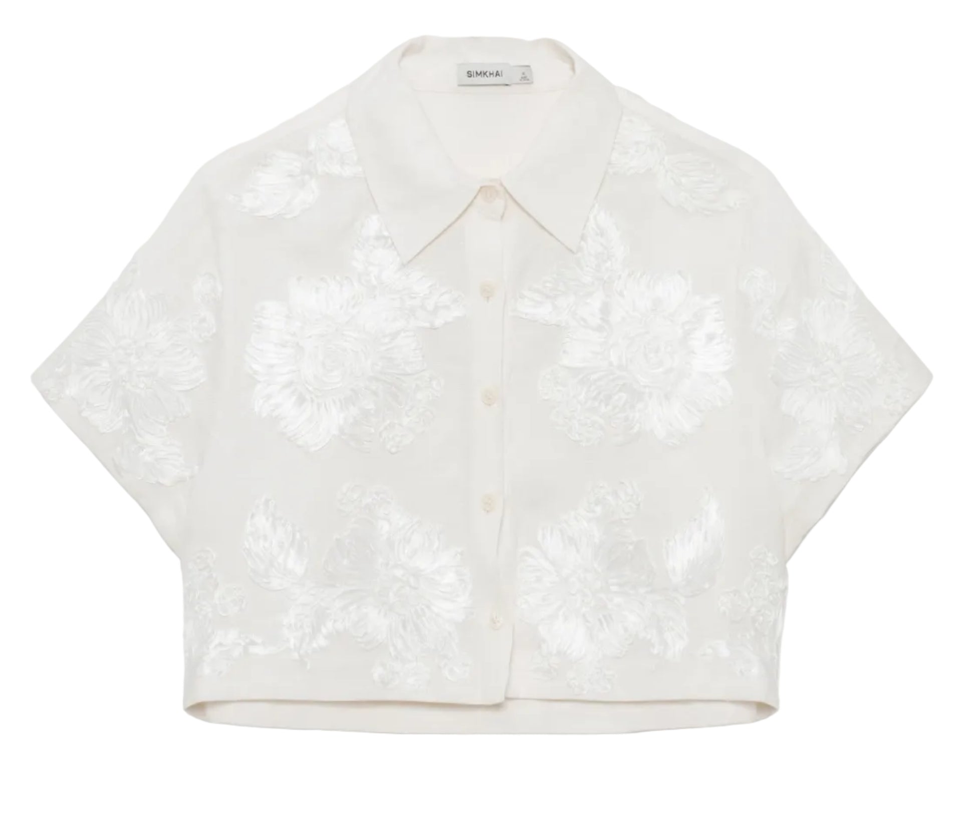 The Simkhai Callie Camp Shirt is a short-sleeved, white cropped top with a collar and textured floral patterns, perfect for a vacation look and shown against a plain background.