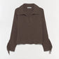 The Natalia Sweater by Simkhai is a long-sleeve, ribbed brown collared sweater with an open neckline, featuring Western-inspired detailing and fringe accents on the lower sleeves, shown against a plain white background.