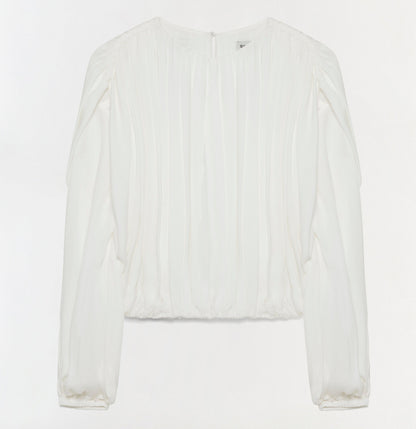 The Simkhai Frida Top is a long-sleeved white silk georgette blouse featuring vertical pleats on the front and subtly gathered blouson sleeves. Displayed against a plain white background, its fluid silhouette brings an elegant touch to any ensemble.