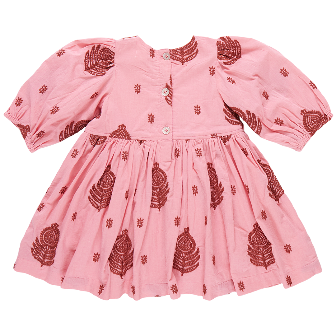 The Pink Chicken Girls' Embroidered Brooke Dress is a charming pink ensemble adorned with intricate red designs and star shapes. It features a buttoned-down front, gathered skirt, and puffed sleeves, seamlessly blending fall patterns with subtle floral embroidery for an elegant touch.