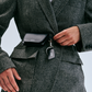 A person in a herringbone blazer attaches the multipurpose Lie Studio Stella Wallet and branded keychain—crafted from Italian cow leather—to their jacket belt area.