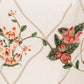Close-up of cream-colored fabric with pink floral embroidery and green leaves in a diamond pattern, used for the Lima Navegante Maxi Dress by Agua By Agua Bendita—ideal for elegant, hand-embroidered details.