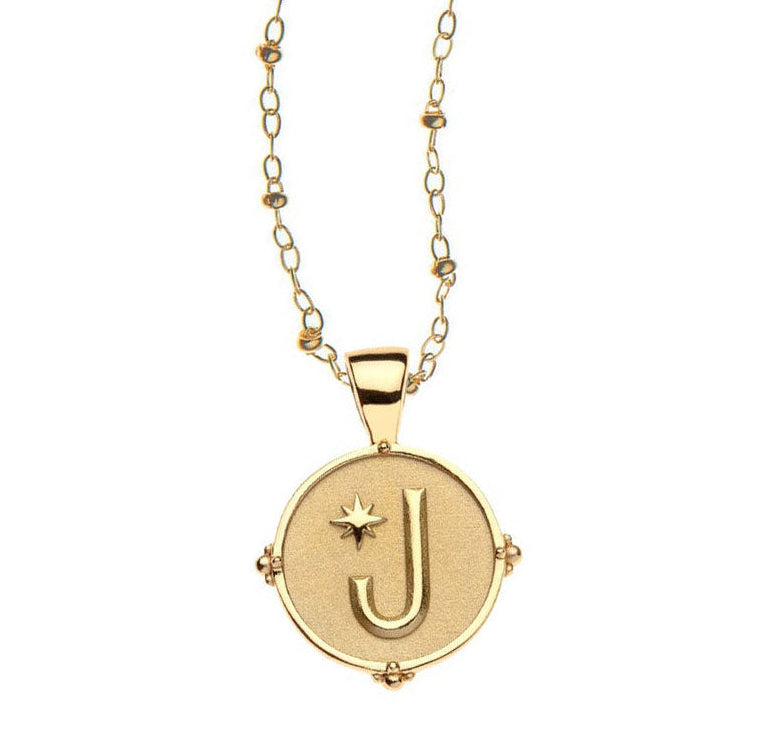 The Jane Win Letter Pendant Satellite Necklace Collection features a 14k gold plated round pendant with a raised letter "J" and star on a textured background—an ideal personalized jewelry piece for everyday style.