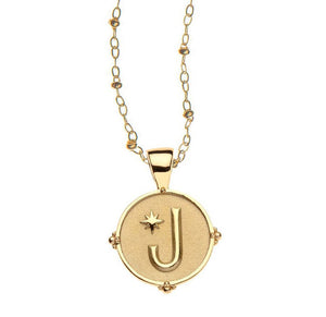 The Jane Win Letter Pendant Satellite Necklace Collection features a 14k gold plated round pendant with a raised letter "J" and star on a textured background—an ideal personalized jewelry piece for everyday style.