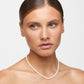 A person with a light skin tone and slicked-back hair wears the Jia Jia Mini Pearl Necklace by Jia Jia, gazing slightly to the side against a plain background.