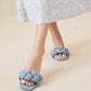 A woman wearing a light blue floral dress and Loeffler Randall Joanna Sandals with a braided upper in blue tweed denim.