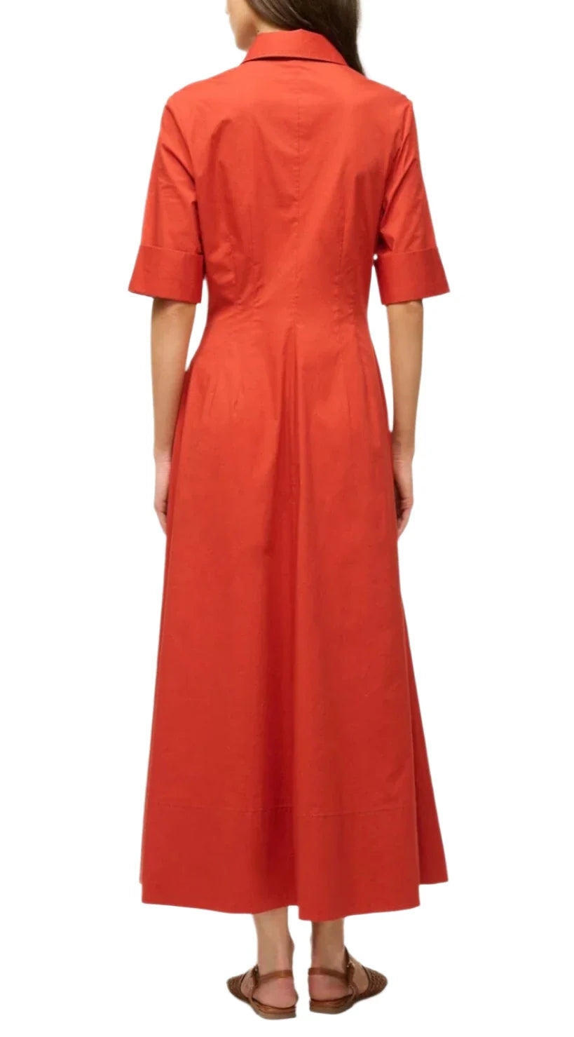 A person is seen from the back wearing the Staud Joan Maxi Dress, crafted in vibrant orange stretchy cotton poplin, paired with sandals against a white background.