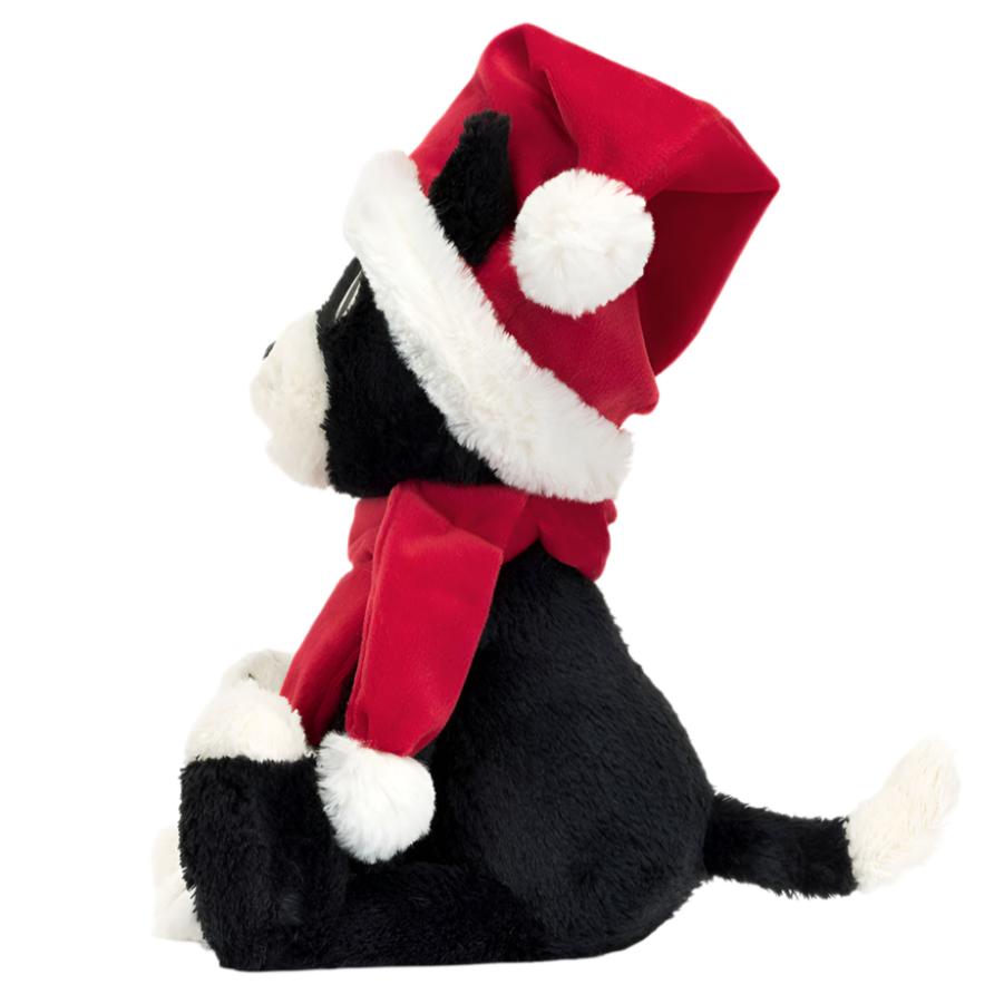 Introducing the Jellycat Christmas Jellycat Jack by Jellycat, a charming black and white plush toy cat featuring a red Santa hat and matching scarf. This festive stuffed animal is showcased in profile view against a white background, perfectly capturing the holiday spirit.