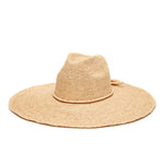 The Jane Hat by Mar Y Sol is a wide-brimmed sun hat made from natural-colored raffia, featuring a slightly creased crown and a decorative band.