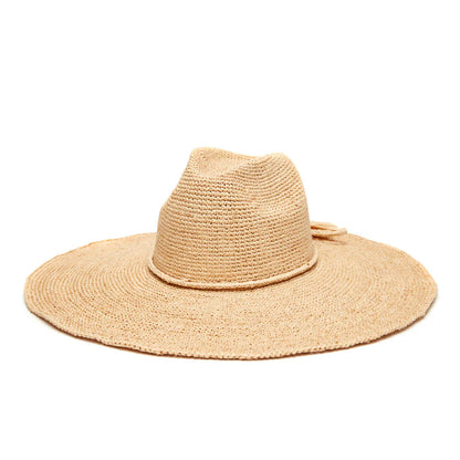 The Jane Hat by Mar Y Sol is a wide-brimmed sun hat made from natural-colored raffia, featuring a slightly creased crown and a decorative band.