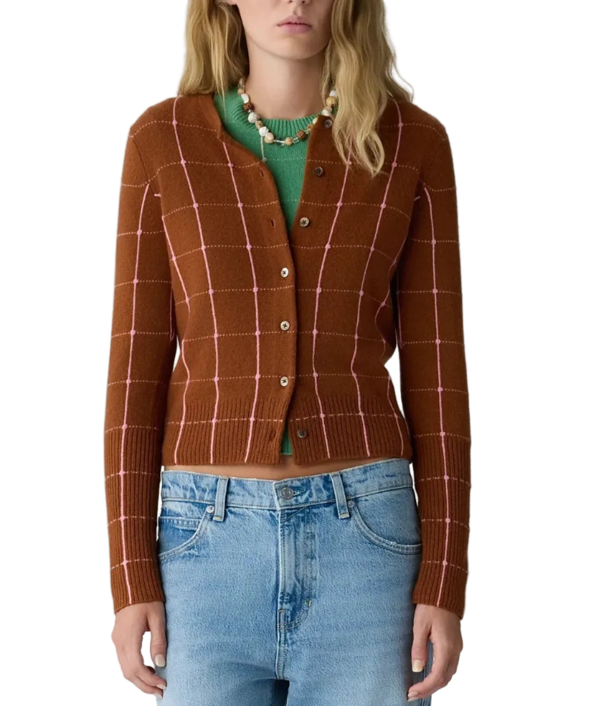 A woman wearing the Guest in Residence Jane Checker Cardigan in brown over a green top, paired with light blue jeans.