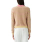 A woman stands facing away in the Guest in Residence Pebble Stripe Jane Cardigan featuring a pink collar, paired with white pants against a plain white background.
