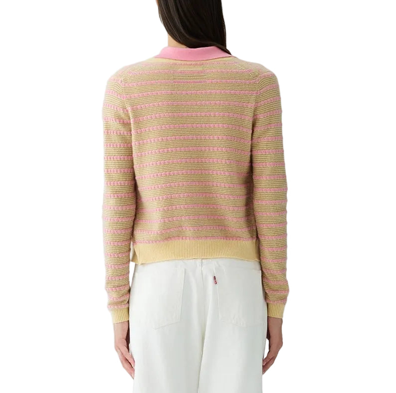 A woman stands facing away in the Guest in Residence Pebble Stripe Jane Cardigan featuring a pink collar, paired with white pants against a plain white background.