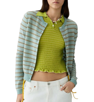 A person wearing the Guest in Residence Pebble Stripe Jane Cardigan in light blue and beige over a green textured top, paired with white pants.