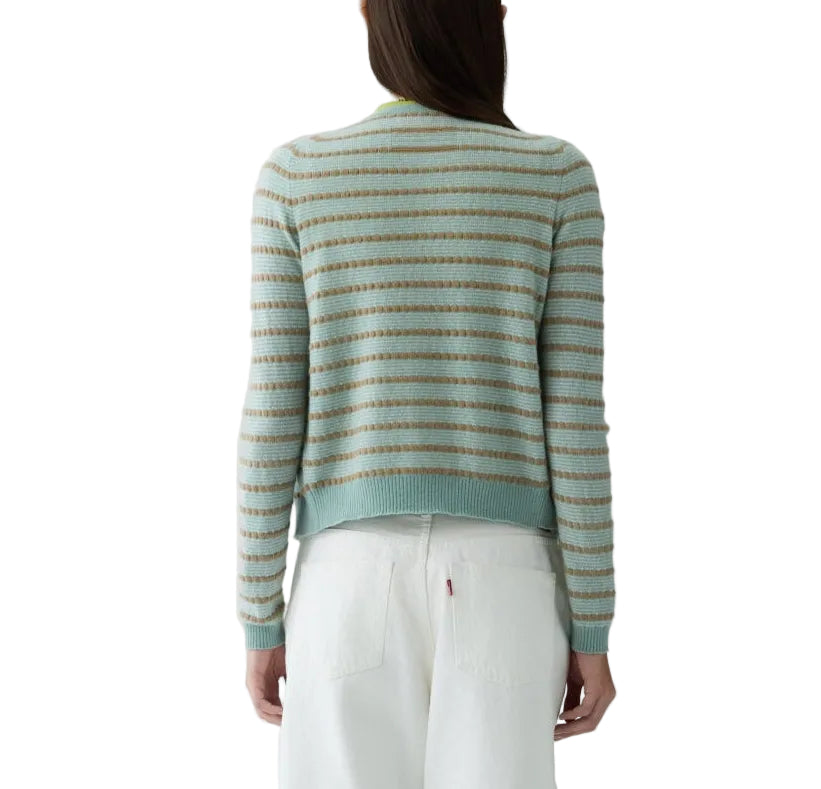 A person with long brown hair, facing away, wears the Guest in Residence Pebble Stripe Jane Cardigan in light blue and beige with white pants. The background is white.