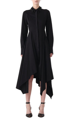 A person stands wearing a black, long-sleeve Jason Wu Collection Asymmetric Dress with Embroidery Collar, paired with strappy black heels.