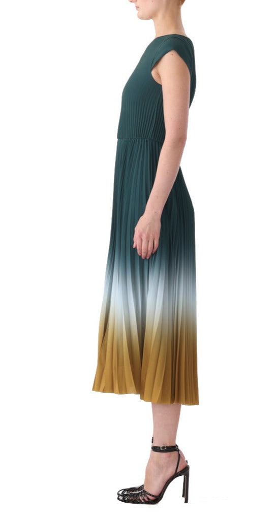 A person standing sideways in a Jason Wu Collection Dip Dye Marocaine Crepe Pleated Dress made from marocain crepe. They are wearing black high heel shoes with ankle straps. The background is plain white.