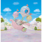A small white Latte Cat baby figurine from Calico Critters sits in the pastel pink Floral Fantasy Skyship, a whimsical carriage with wings and three round lanterns, set against an enchanting outdoor backdrop.
