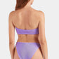 A woman with long brown hair is shown from behind wearing the Jean Bikini by Hunza G, a textured lavender-colored crinkle fabric two-piece, against a white background.